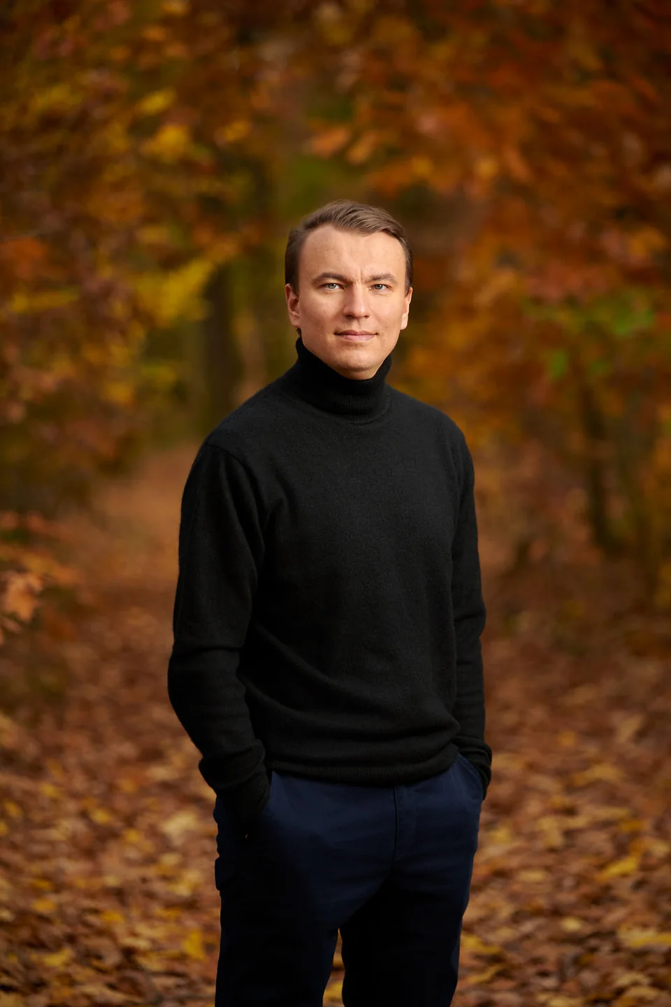 Stan Sabitovs outdoors beside autumn trees.