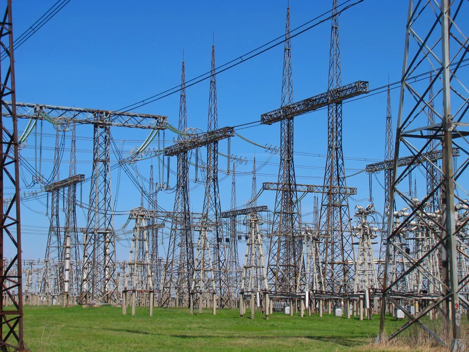 Steel gantries, busbars, insulators and switching equipment in an outdoor electricity substation.