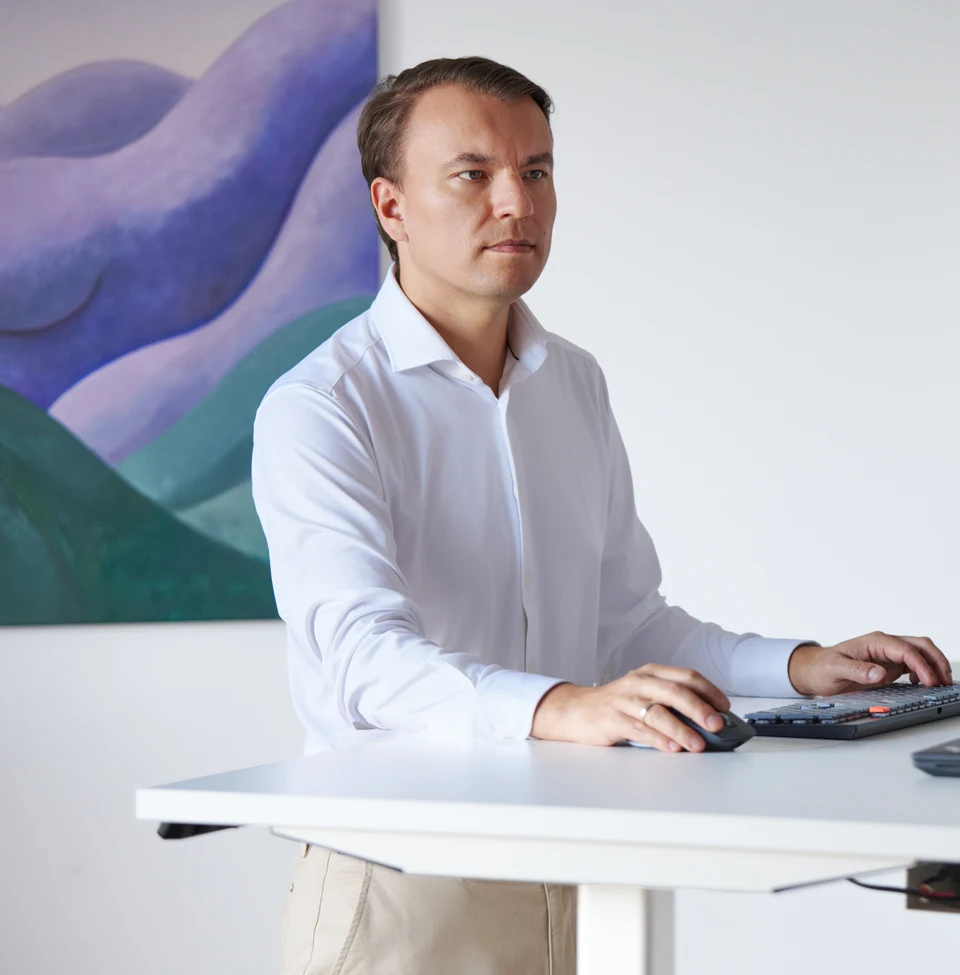 Stan Sabitovs working at a computer in a bright office.