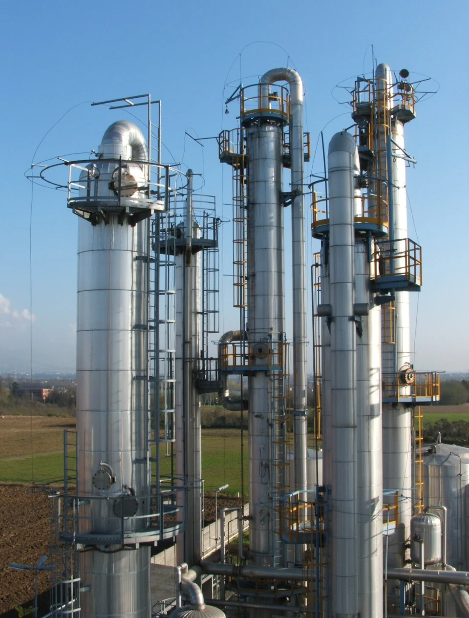 Three tall insulated process columns with platforms, ladders and interconnecting pipework.