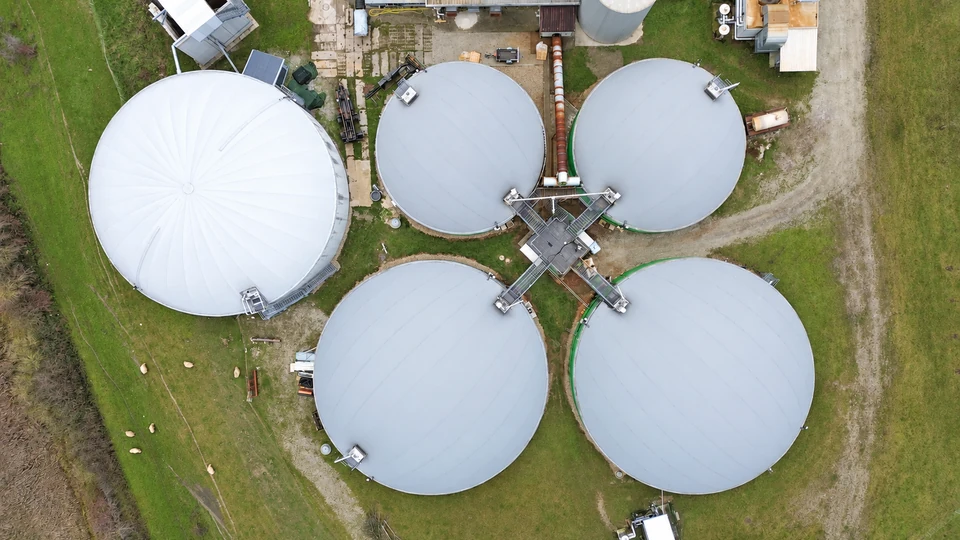 Overhead view of covered circular tanks and connected equipment at a biogas plant.